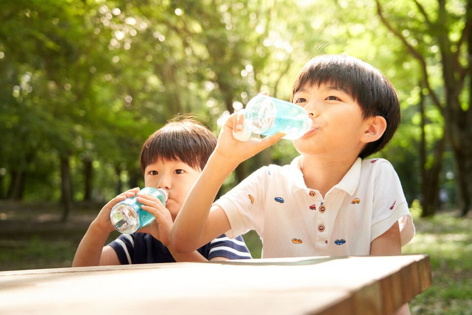 公園でアルカリイオン整水器で作った水を飲む子ども