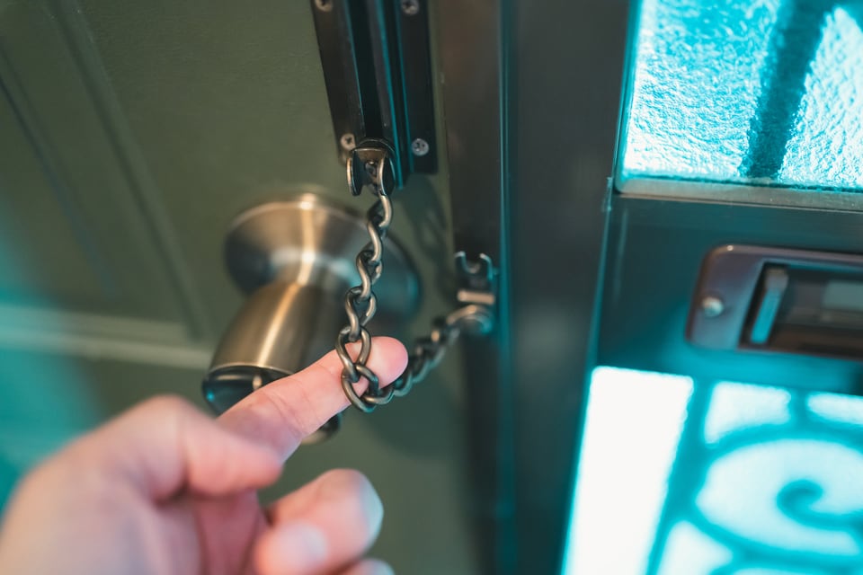 ドアチェーンが掛かっているか確認している男性