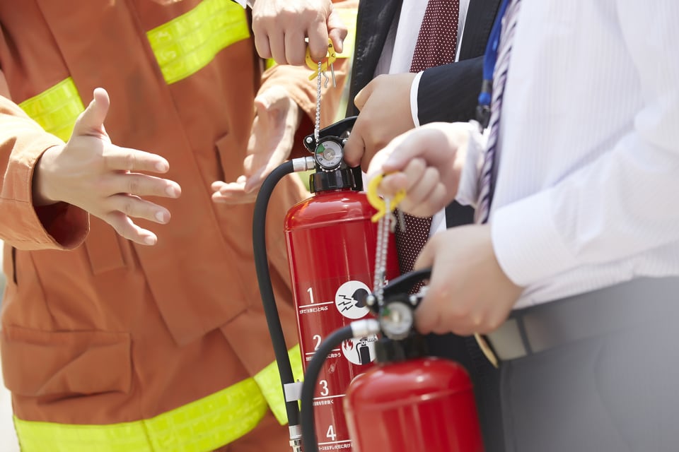 防火区画検証法順守のため、消防士から消火器使用の指導を受ける住民