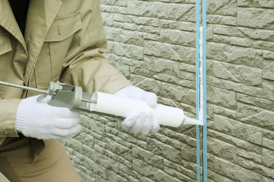 外壁の隙間にシーリング材を充填している作業員