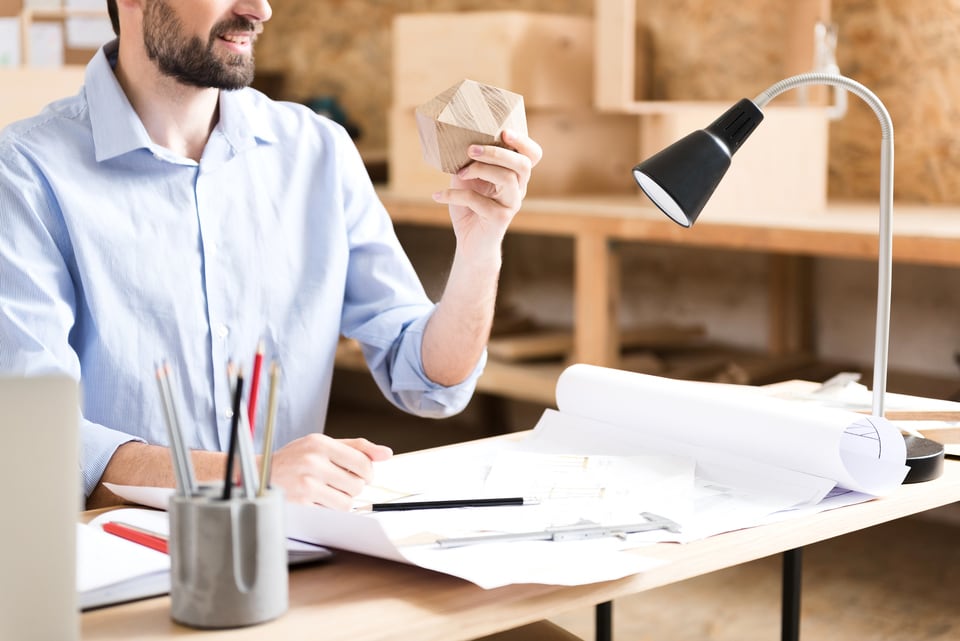 デスク上のタスク照明を灯して仕事をする男性