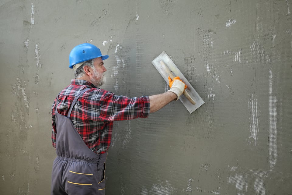 壁にモルタル塗装を施している職人