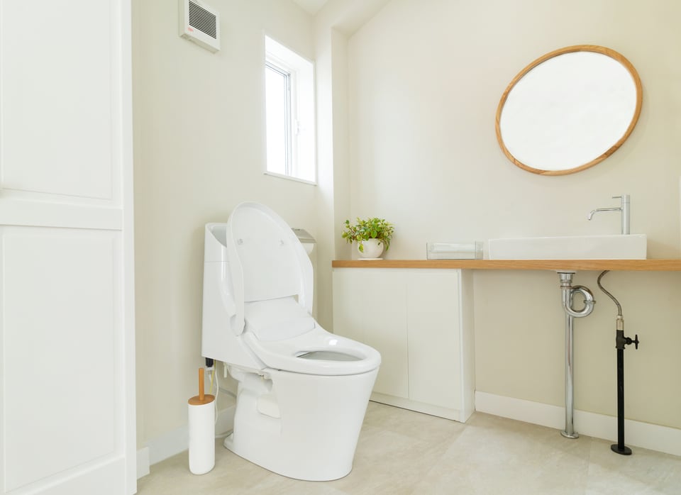 白と木目調を基調としたトイレルームに設置された温水洗浄機能付きO型便座