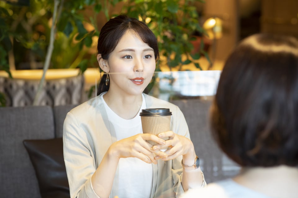 飛沫対策として立てられるアクリル板越しにお茶を楽しむ女性