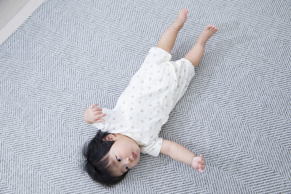 アンダーレイを使用した床に寝転ぶ赤ちゃん