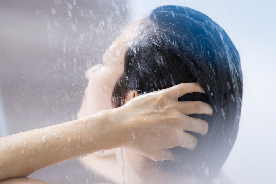 多機能シャワーを使ってシャワーを浴びる女性