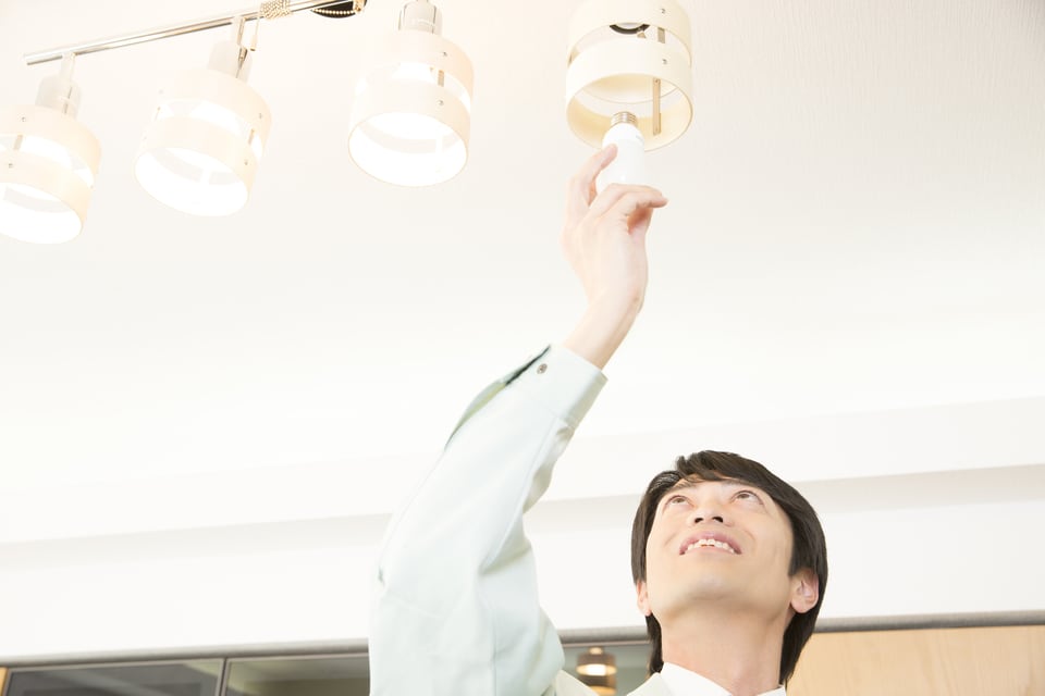 天井に取り付けた多灯照明の電球を替える男性