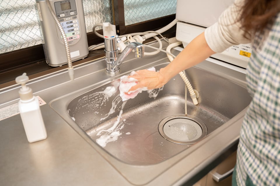 汚れやすいキッチンの水回りを掃除する女性