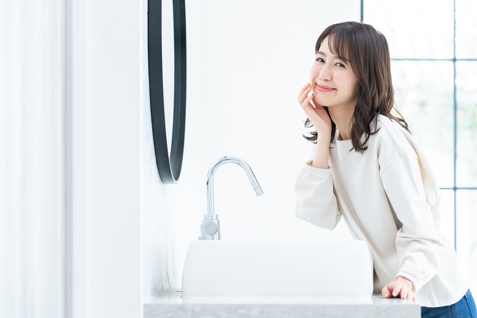 白を基調とした洗面化粧台の前に立つ女性