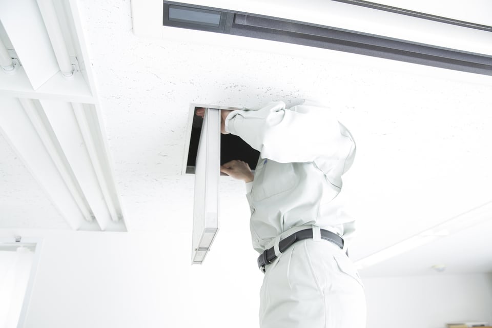 新築住宅の天井点検口から屋根裏をチェックする作業員