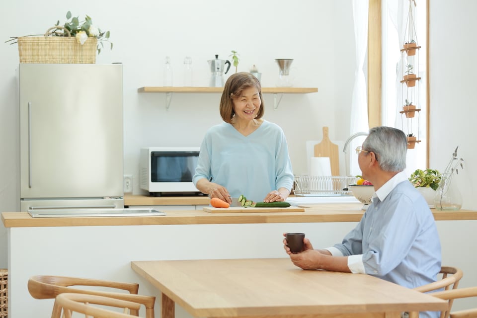 オープンキッチンで笑顔で会話するシニア夫婦