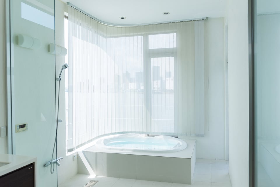 広めの半埋め込み式浴槽のある明るいバスルーム