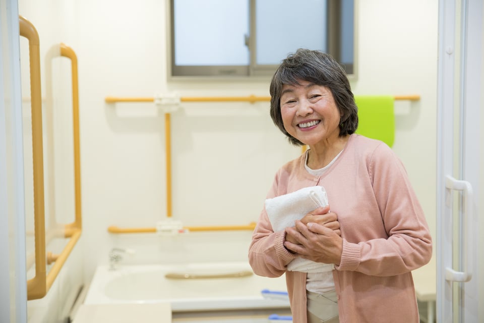 L型手すりのある浴室を利用する女性