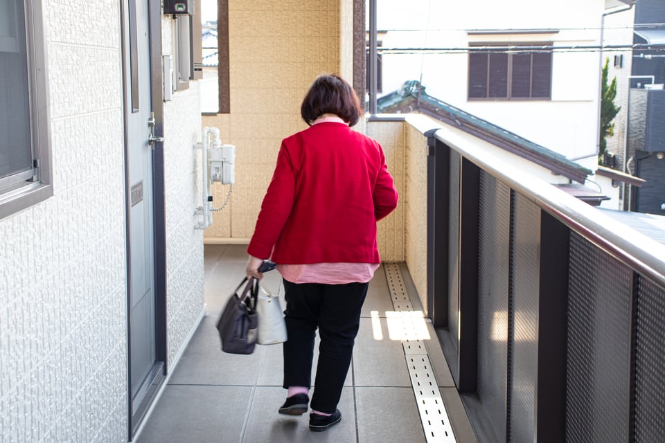 マンションの共用廊下を歩く女性