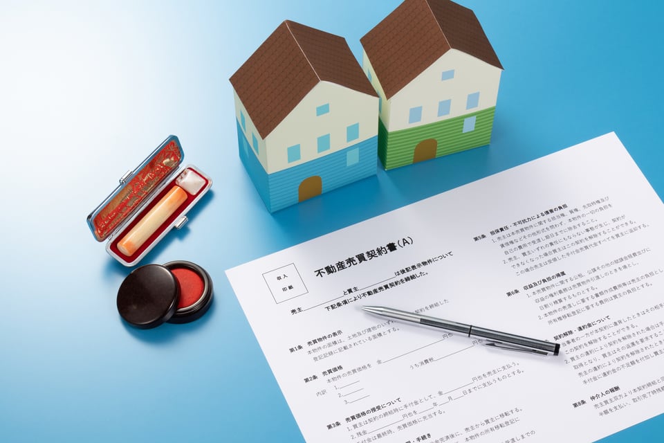 売主と結んだ不動産売買契約書と印鑑と家の模型