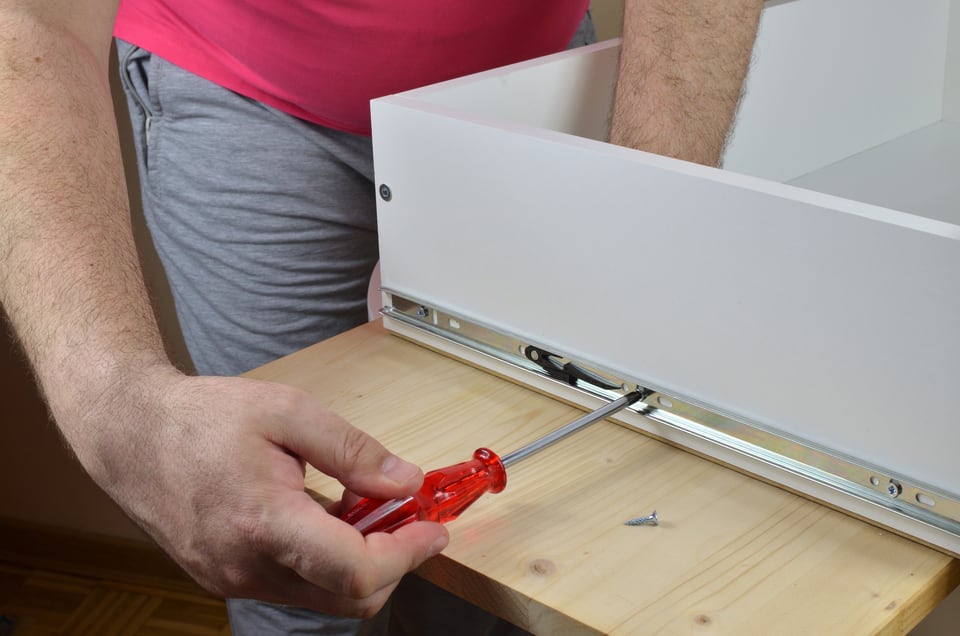 DIYで引き出し側にスライドレールを設置する男性