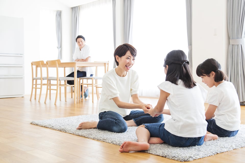 ハイサッシの前に座る父親とラグに座って遊ぶ母親と二人の娘
