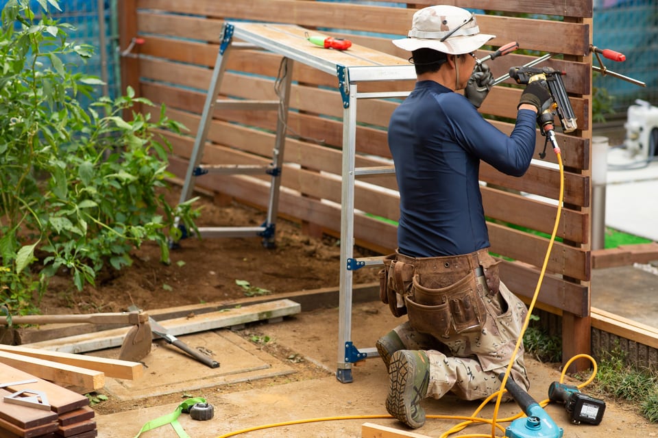 DIYで庭に木製のフェンスを設置する男性