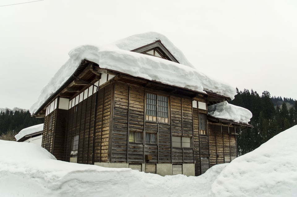 多雪地域に建つ古民家の屋根に雪が積もる様子