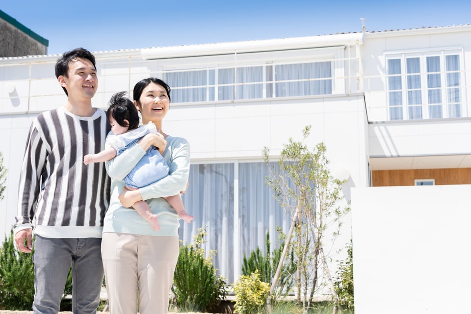 購入した持家を見上げる若い家族