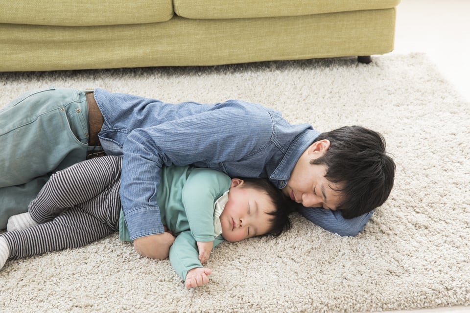 床に寝転がって温水式床暖房の温かさを実感する親子