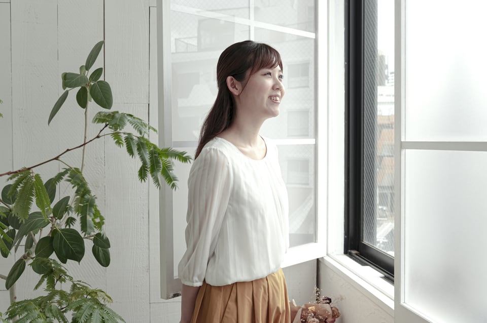 窓を開けて自然換気をする女性