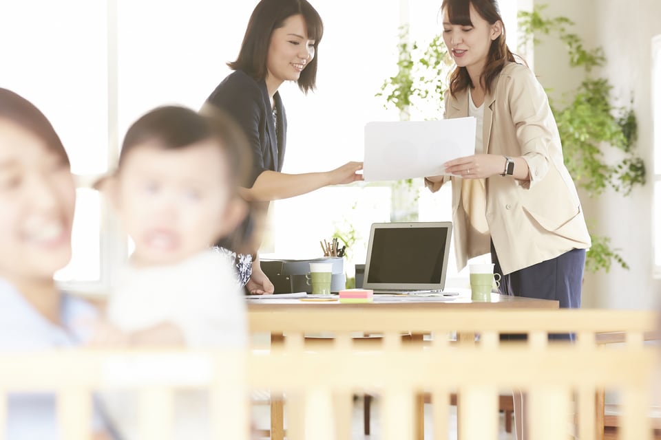 オフィス内にある託児所に子どもを預ける相談をする母親