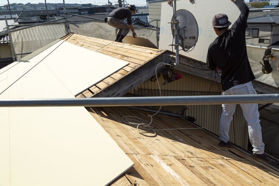 住宅の屋根に野地板を貼る職人