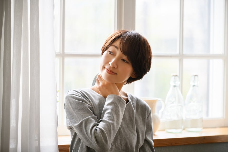 採光や風通しに優れた腰高窓の前でストレッチをする女性