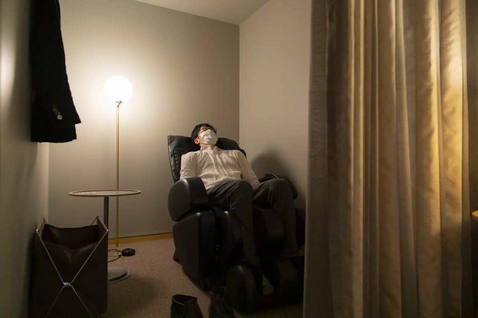 アコーディオンカーテンで仕切られた部屋で休憩する男性