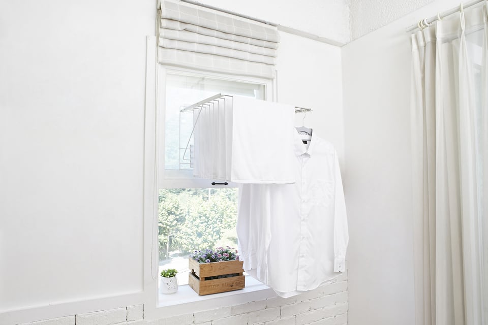 シェードを引き上げた窓の下に洗濯物が掛かっている様子