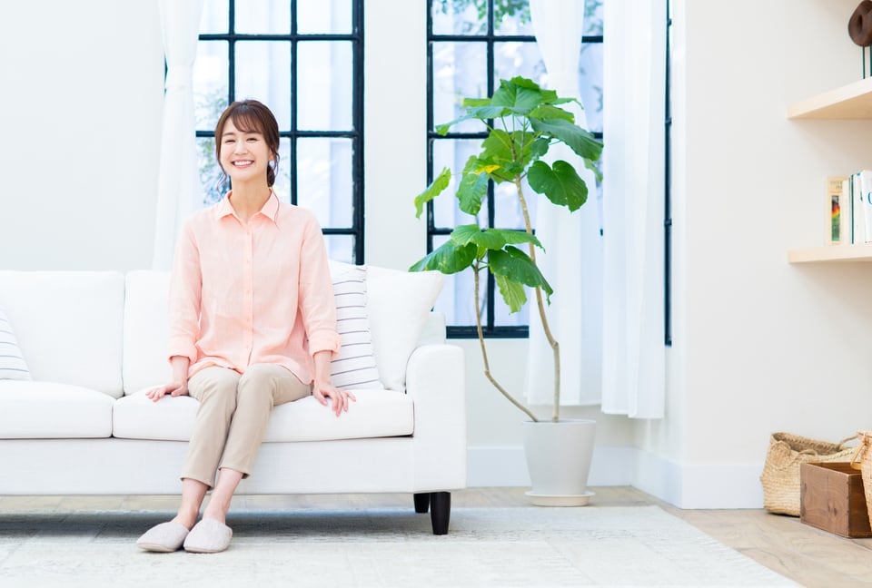 リビングルームにある白いソファに座る笑顔の女性