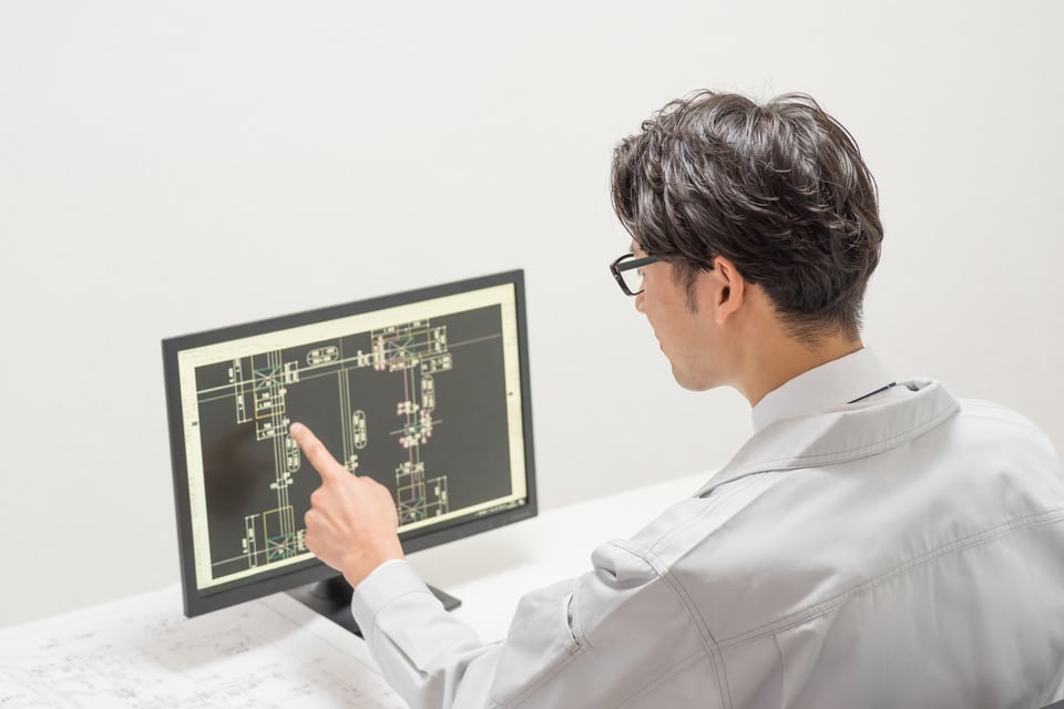 プレカットを行う木材のサイズを図面を見て確認する男性