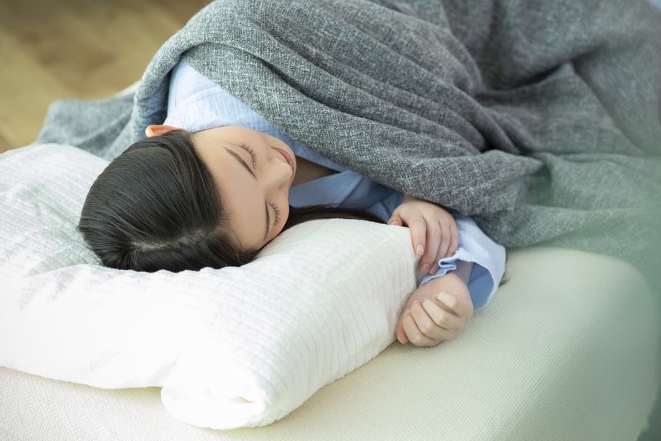 マットレスの上で横になった、パジャマ姿の女性