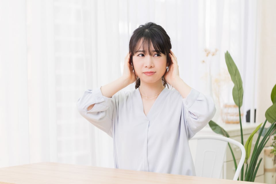 交通騒音により会話を邪魔され耳をふさいでいる女性