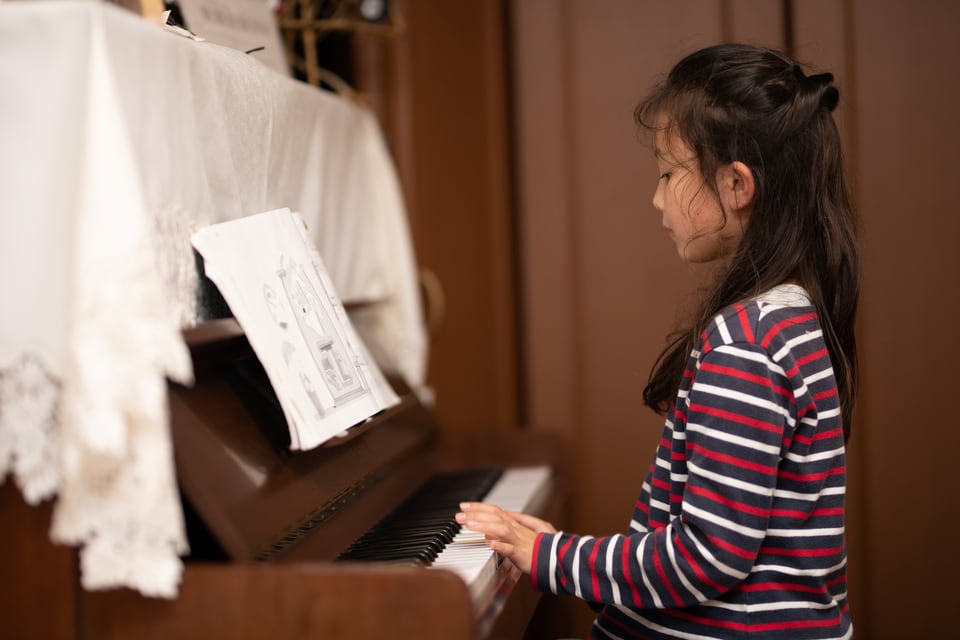 遮音カーテンのある部屋でピアノを弾く女の子