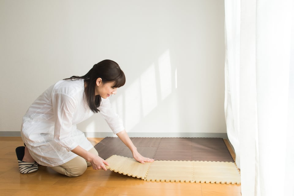 騒音対策として、床にマットを敷く女性