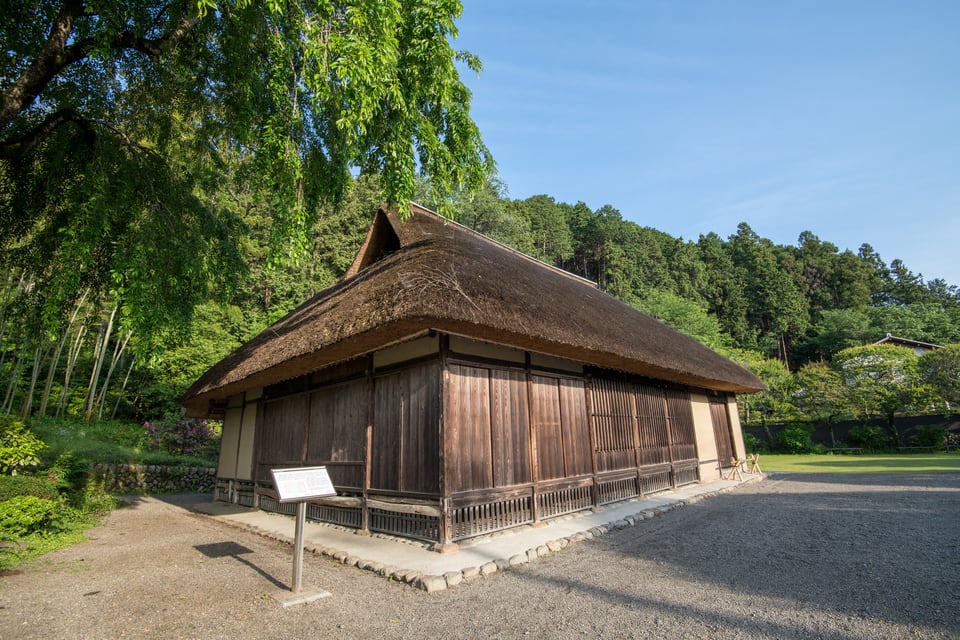 緑の中にある入母屋造の屋根を持つ建築物