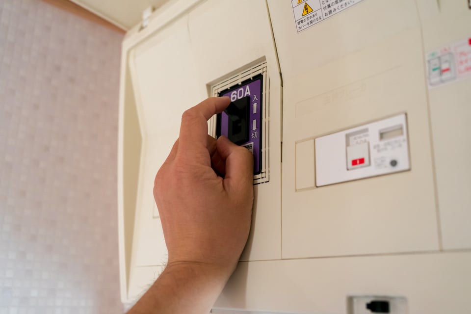 アンペアブレーカーを上げて電気を復旧させる男性
