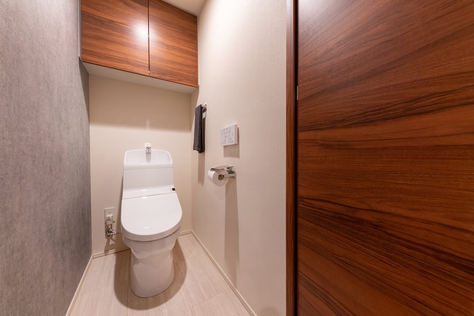 吊り戸棚タイプの木目調トイレ収納のあるトイレ