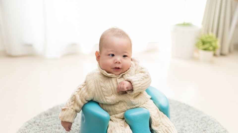 座面の低いロータイプのベビーチェアに腰掛ける乳児