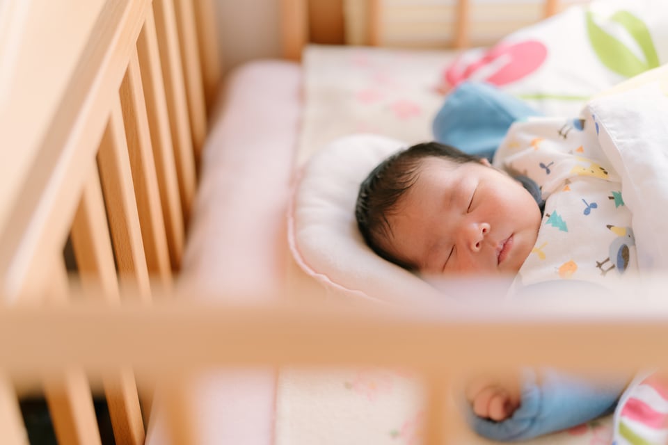 ベビーベッドですやすや眠る乳児