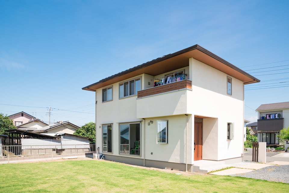 穏やかさを感じさせる白の外装材を使った、広い庭のある戸建住宅