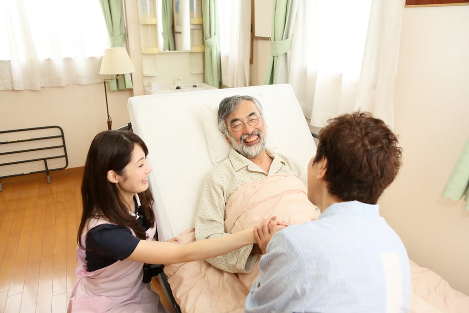 特殊寝台を利用する高齢男性と介護するヘルパー
