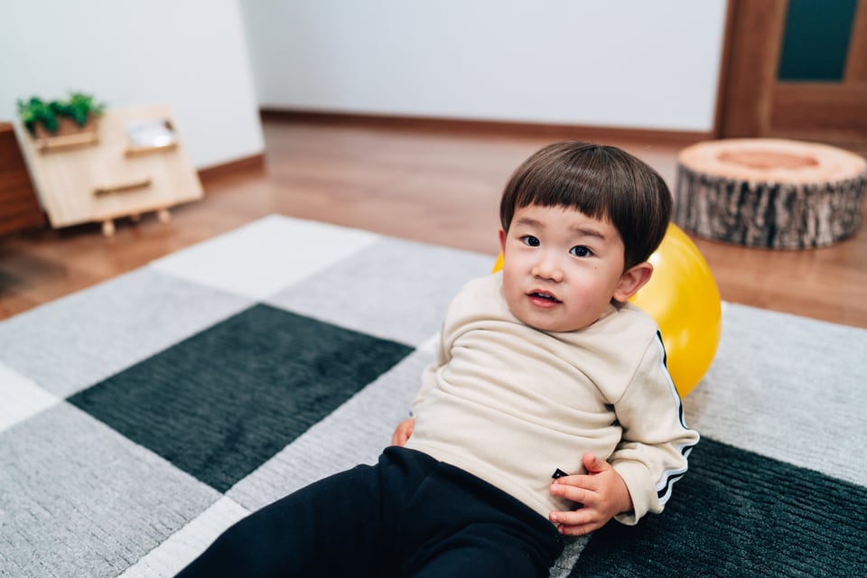 防音マットを下に敷いたカーペットに寝転ぶ子ども