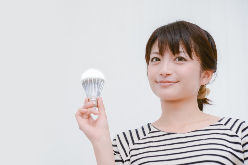 ルーメンで明るさが表されるLED電球を持っている女性