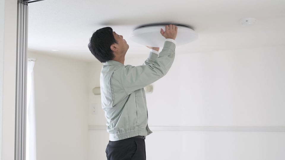 天井に一灯照明を取り付ける様子