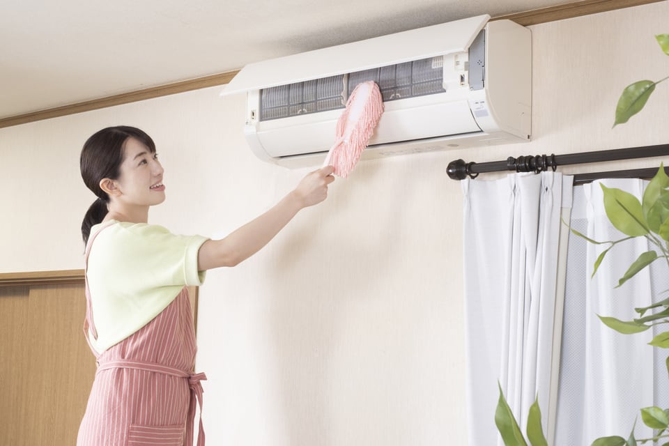 善管注意義務違反とならないよう設備のエアコンを掃除する女性